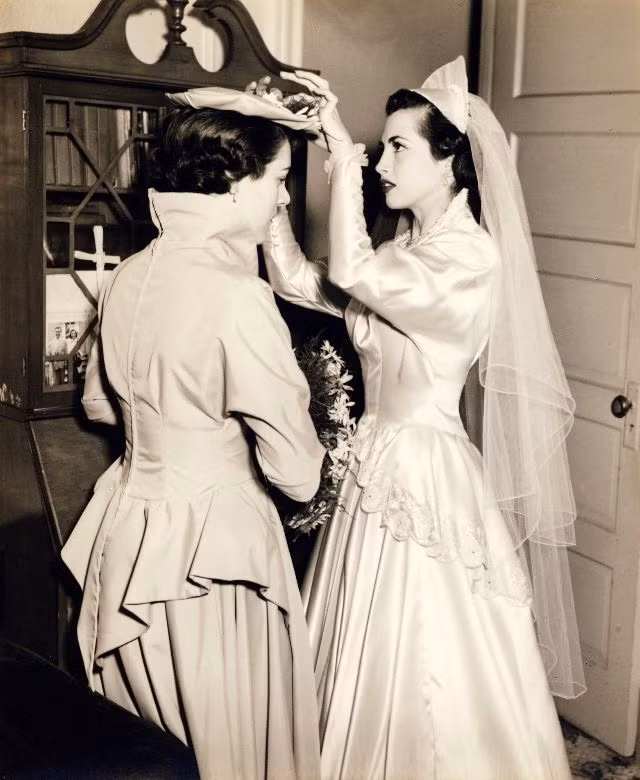 Cô Clara điều chỉnh chiếc mũ của người mẹ đỡ đầu. Ảnh: Robert Barone Flickr.