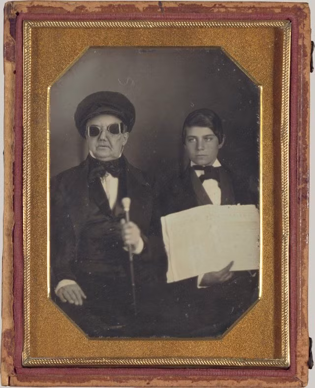 Chân dung một người đàn ông mù và trợ lý - người giúp ông đọc báo và các văn bản, được chụp vào khoảng năm 1850. Thông tin cá nhân về người trong ảnh không còn được lưu giữ.