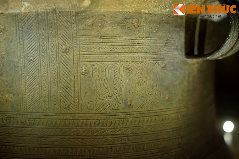 Thân trống có 7 vành hoa văn. Vành số 1 là hoa văn chấm giữa, hoa văn gạch chéo vào vòng tròn tiếp tuyến, chia làm 6 ô theo chiều dọc, trong mội ô có hai người hóa trang lông chim, chuyển động từ trái sang phải, tay cầm rìu chiến và tay cầm mộc hình đầu chim.