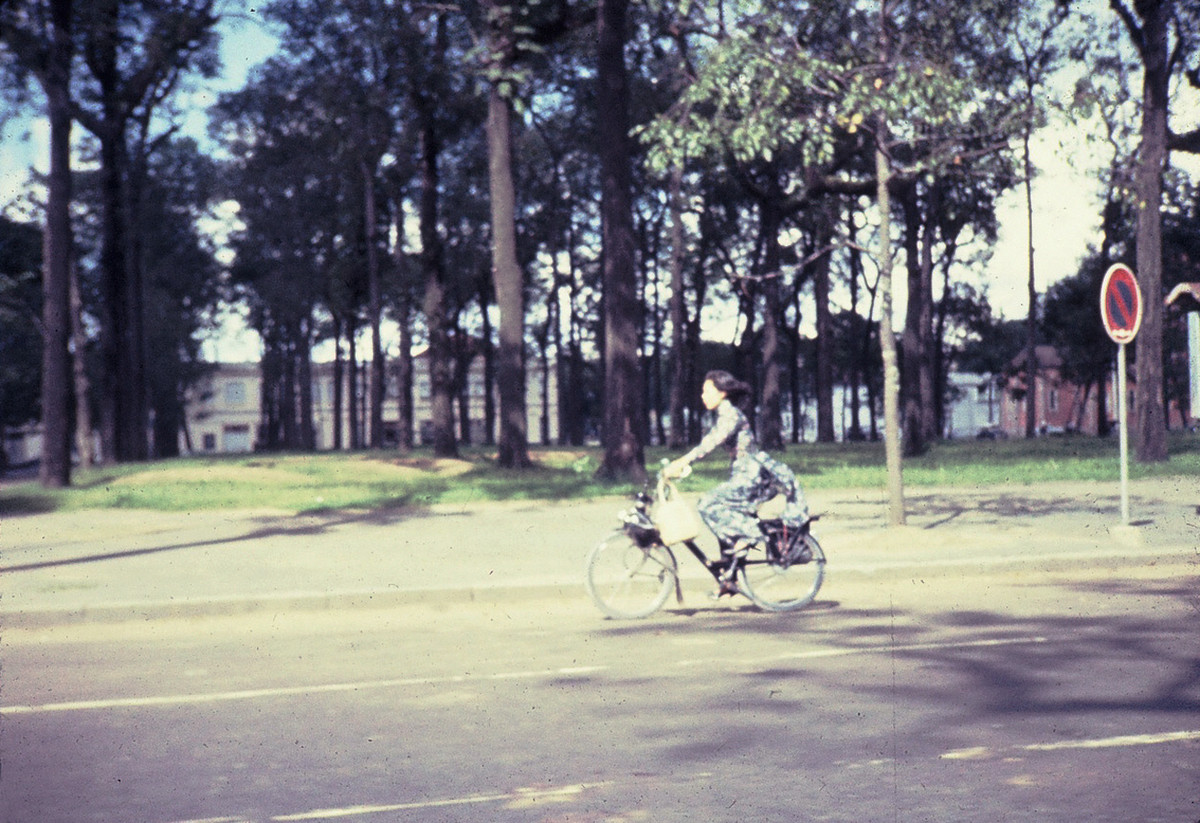 Người phụ nữ Sài Gòn mặc áo dài đạp xe trên đường Pasteur. Ảnh: Dale Ellingson.