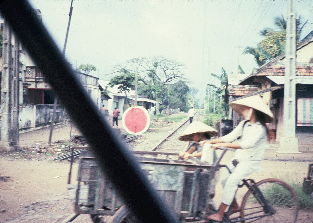 Thiếu nữ đạp xe ba gác băng qua đường tàu. Ảnh: Dale Ellingson.