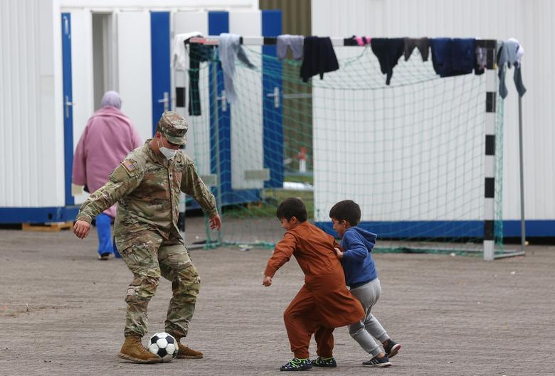Một binh sĩ chơi đá bóng cùng các em nhỏ tị nạn tại doanh trại của quân đội Mỹ ở Kaiserslautern, ngày 30/8.