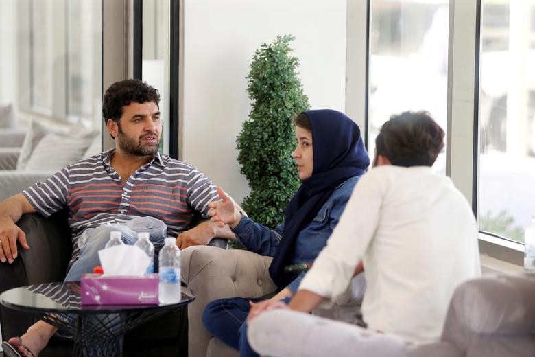 Một vài người ngồi chờ nhận đồ được phân phát miễn phí tại một khu nhà tạm trú ở Doha, Qatar, ngày 27/8.