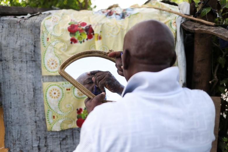 Manithe Simon, 68 tuổi, cạo râu bên ngoài ngôi nhà lụp xụp của ông ở Marceline gần Lea Cayes, ngày 22/8.