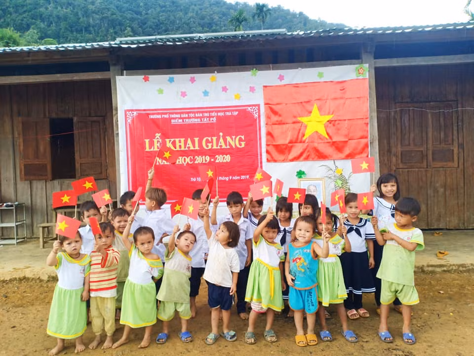 Các em cùng giơ lá cờ tổ quốc chụp hình chào mừng khai giảng.