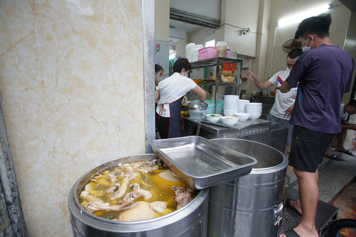 Để đảm bảo giãn cách, nhiều hàng phở bố trí người hướng dẫn khách ngồi chờ bên ngoài cửa hàng.