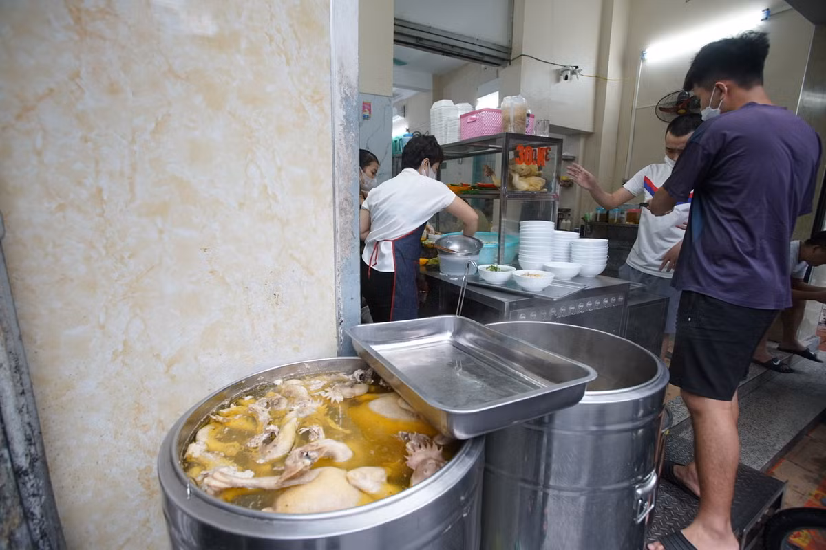 Để đảm bảo giãn cách, nhiều hàng phở bố trí người hướng dẫn khách ngồi chờ bên ngoài cửa hàng.