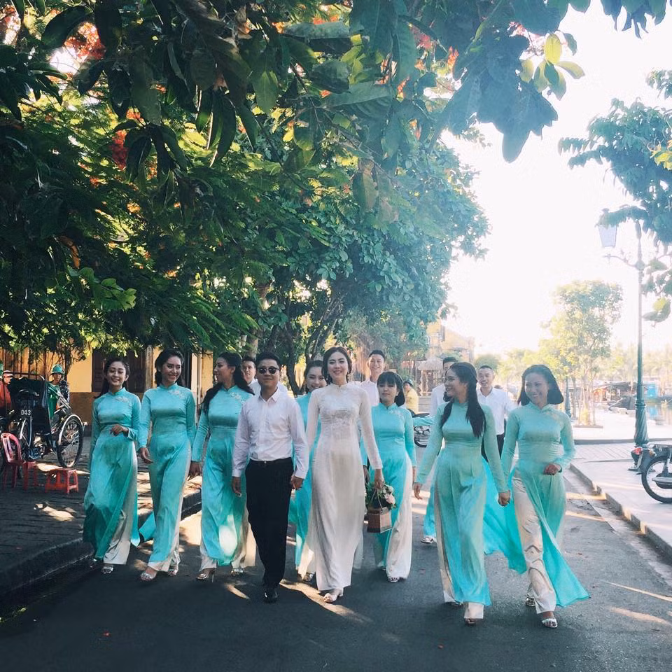 Đôi vợ chồng rạng rỡ nắm tay nhau bên dàn phù dâu xinh đẹp, trong con mắt tò mò xen lẫn ngưỡng mộ của người đi đường.