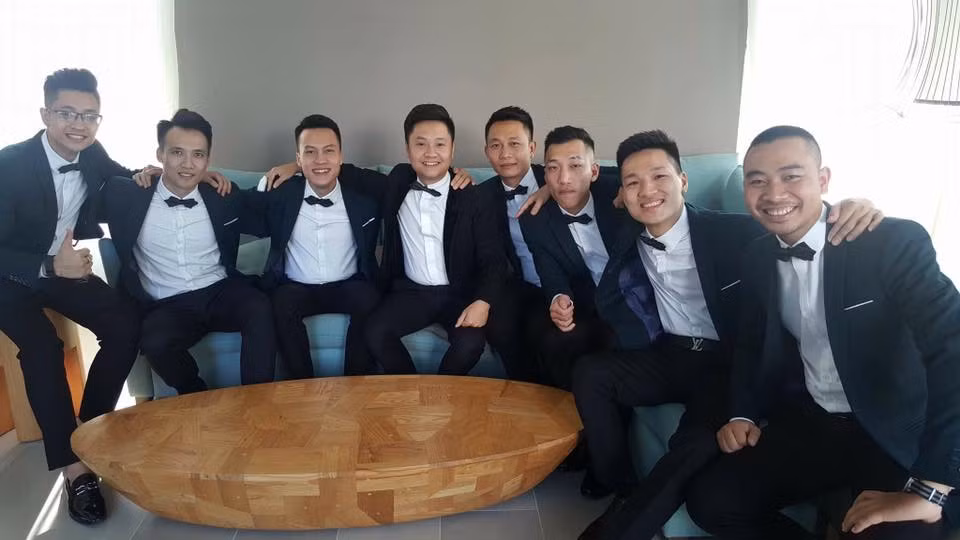 Chú rể đẹp trai ngồi giữa cười hạnh phúc trong đội phù rể.