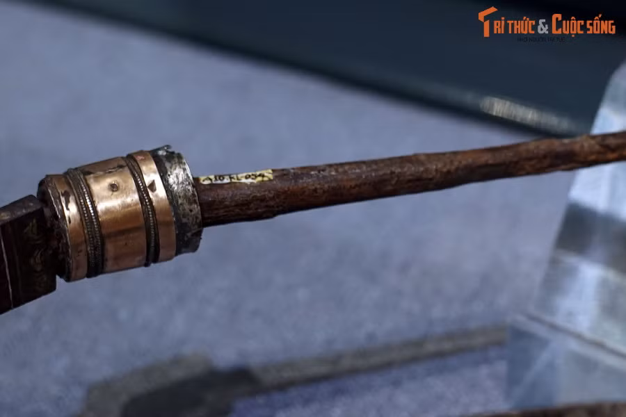 Phần cán chỉ còn lại lõi thép bên trong dài 18,5 cm, lá chắn, chuôi và chốt chuôi đều đã mất. Đai đao dài 1,8 cm, làm bằng hợp kim đồng, bề mặt được mài bóng, hai viền đai khắc những đường chỉ rất tỉ mỉ.