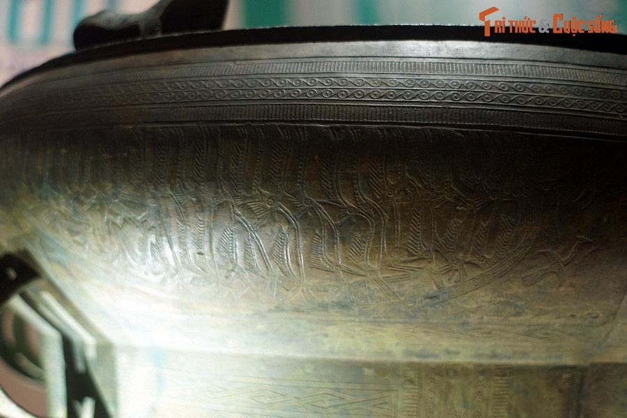 Phía trên tang trống có các vành trang trí hoa văn vòng tròn, vạch ngắn. Phía dưới đúc nổi 6 hình thuyền.