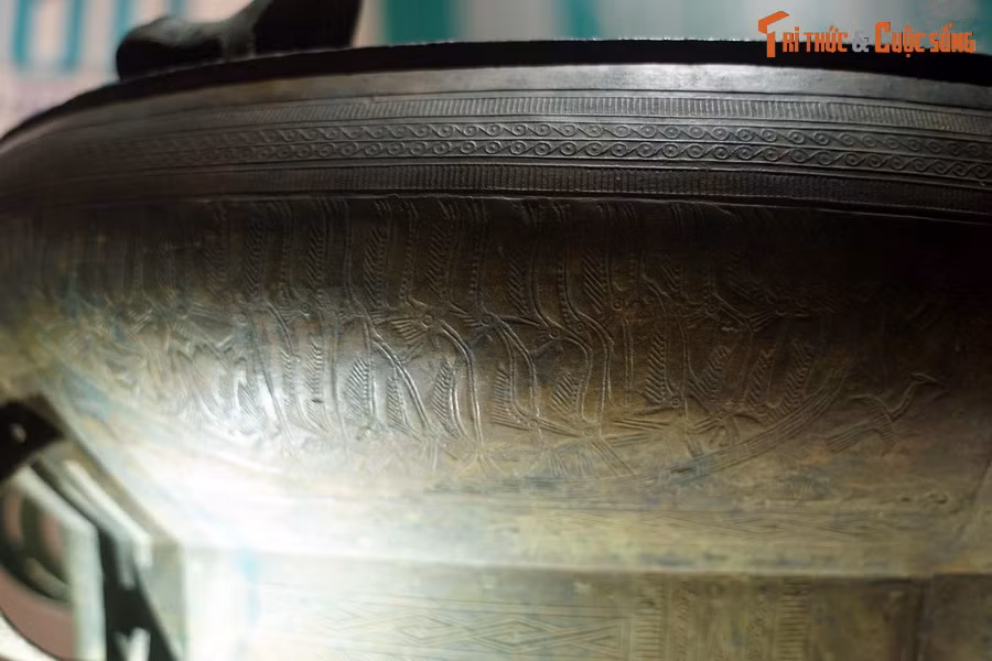 Phía trên tang trống có các vành trang trí hoa văn vòng tròn, vạch ngắn. Phía dưới đúc nổi 6 hình thuyền.