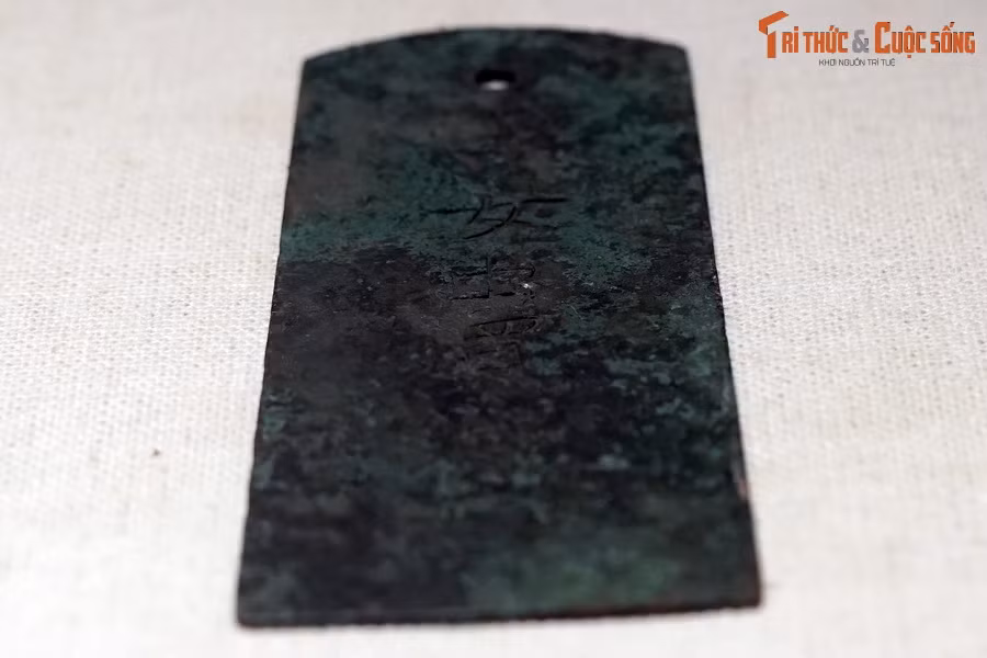 Được phát hiện và bảo quản, trưng bày tại Di sản thế giới Hoàng thành Thăng Long, hiện vật này là tấm hợp kim đồng, phẳng, mỏng, hình thang cân, hai góc của cạnh trên của hình thang được tỉa cong.
