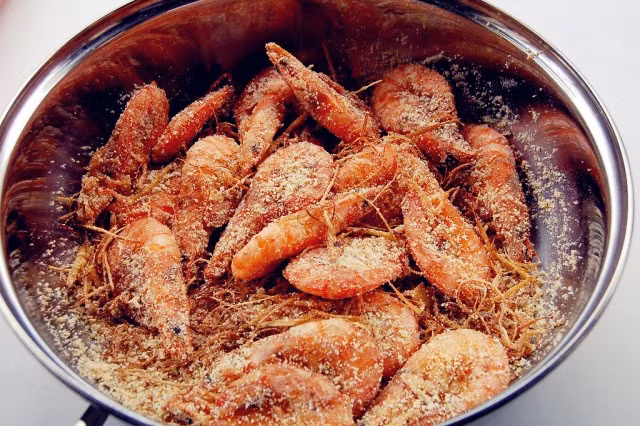 Sau khi rán tôm xong cho 1 thìa muối hạt vào chảo rang tới khi muối nổ tí tách thì đổ ra giã dập muối cho vụ hẳn ra. Ảnh: Bepgiadinh.