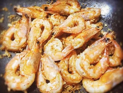 Cuối cùng cho toàn bộ số tôm đã chiên qua vào chảo gia vị muối tỏi rồi xóc thật đều lên cho gia vị bám kín con tôm là có thể thưởng thức.