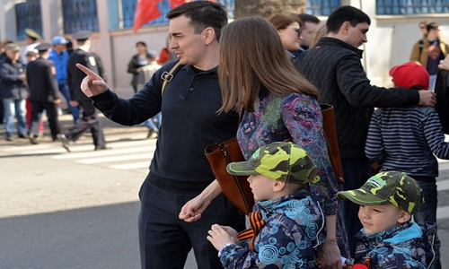 Hai anh em sinh đôi với quần áo giống nhau cùng dải băng thánh George xúng xính đi xem duyệt binh cùng bố mẹ.