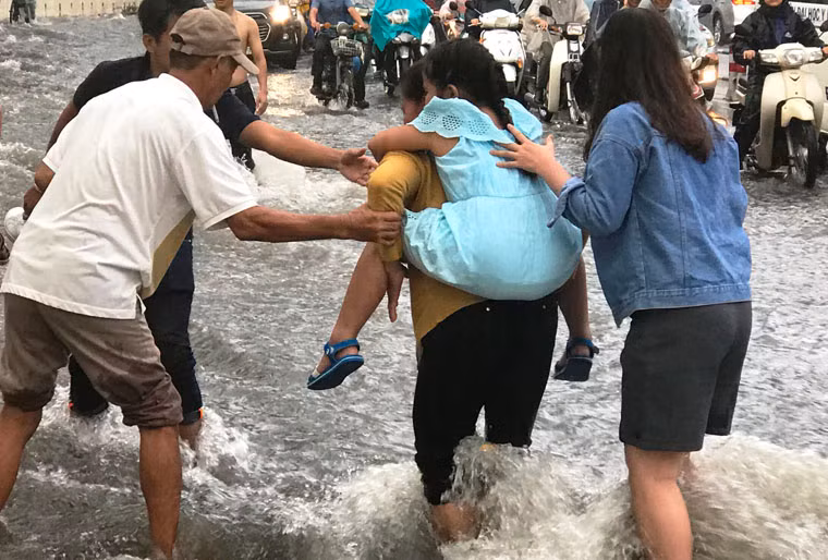 Những đứa trẻ được người lớn nhanh chóng tìm cách thoát khỏi khu vực ngập nước hết sức nguy hiểm.