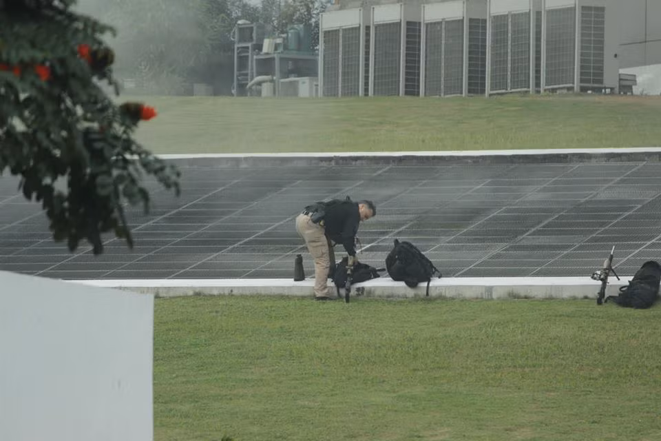 Một mật vụ lấy súng ra từ balo.