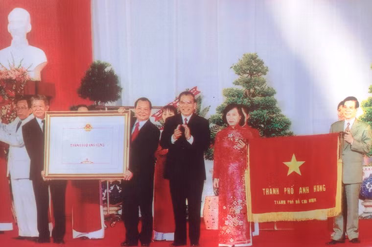 Sau ngày thống nhất, người dân và lãnh đạo TP HCM cùng chung tay xây dựng cuộc sống mới. Với sự cố gắng, nỗ lực và những thành tựu đạt được, TP HCM vinh dự được Đảng, Nhà nước phong tặng nhiều danh hiệu cao quý: Thành phố Anh hùng, Anh hủng Lực lượng Vũ trang nhân dân, Anh hùng Lao động thời kỳ đổi mới, Huân chương Sao Vàng. Ảnh ngày 1/9/2005, TP HCM vinh dự đón nhận danh hiệu "Thành phố Anh hùng". Ảnh Hữu Luận.