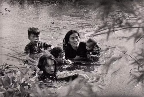  14. Chiến Tranh ở Việt Nam: Tháng 9/1965. Bình Định. Người mẹ và bọn trẻ vượt sông, thoát khỏi lửa đạn. Tác giả Kyoichi Savada.