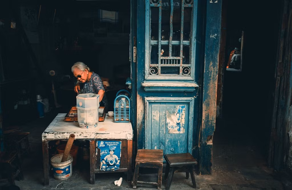 Cụ bà bán trà đá ở Ô Quan Chưởng. Bà cho biết năm nay đã hơn 80 tuổi, bán nước cũng đã chục năm rồi. "Nhà chẳng thiếu gì, nhưng cứ thích ngồi bán cho vui, nghe chuyện của thiên hạ", bà tâm sự.