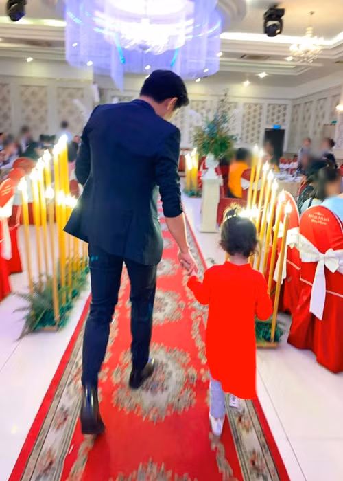 Quý Bình nắm tay con trai của Ngọc Tiền tại một bữa tiệc.