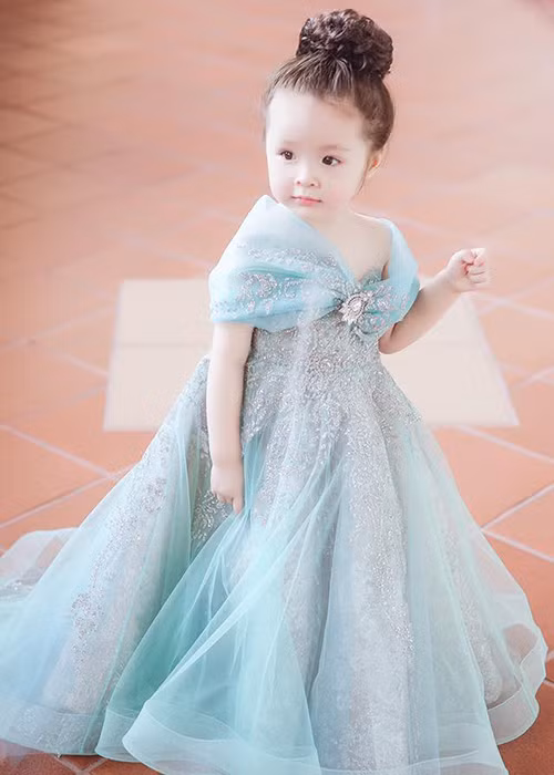 Mái tóc xoăn màu nâu hạt dẻ tự nhiên được búi cao gọn gàng, tôn gương mặt bầu bĩnh, đáng yêu của cô nhóc.