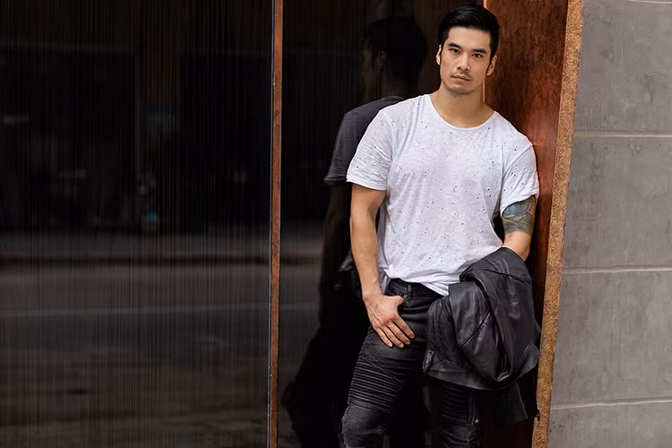 Hình ảnh chàng trai cá tính, phong trần được nam diễn viên 8x tái hiện rõ nét qua set đồ gồm: áo phông, jeacket da phối và quần jeans loang màu.