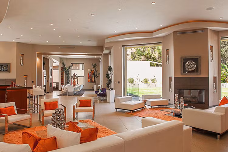 Phòng khách trong biệt thự của Rihanna sử dụng màu sắc trung tính, các khu vực được phân chia tinh tế bằng những tấm thảm màu cam nổi bật. 