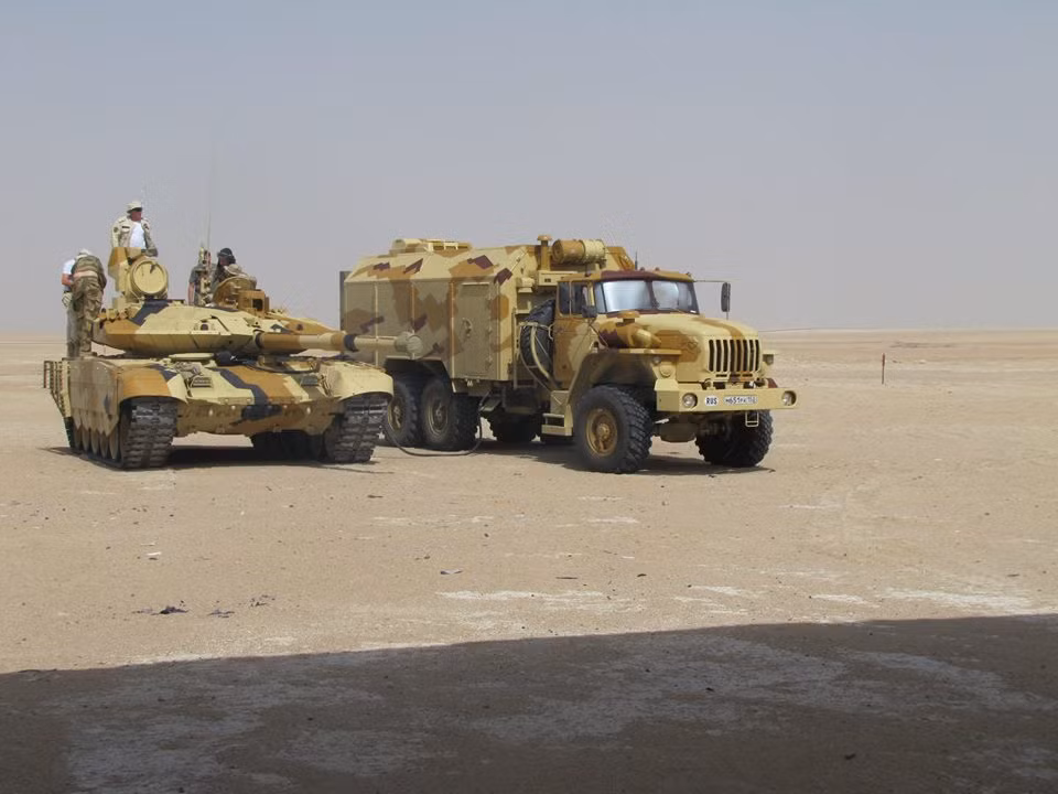 Trong ảnh, xe tăng T-90MS đứng cạnh xe hậu cần dựa trên khung gầm Ural-4320 đang thử nghiệm trên thực địa tại một quốc gia bí ẩn.