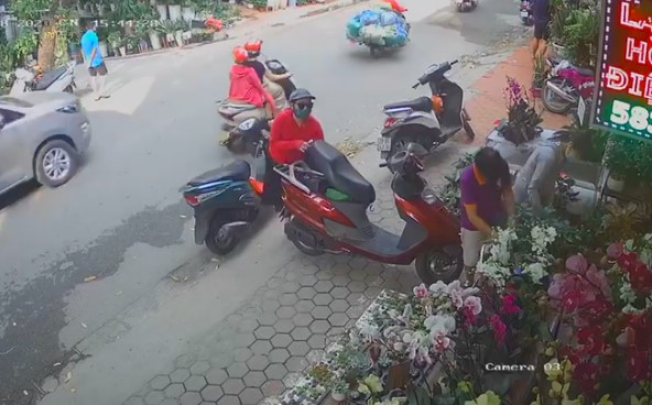 Theo đó, đoạn video camera ghi lại cảnh một nữ khách hàng dựng xe trên vỉa hè rồi vào cửa hàng hoa. Trong khi vị khách đang mải mê chọn thì một người phụ nữ khác, mặc áo đỏ đi xe máy từ từ tiến tới, rồi nhanh tay cậy cốp xe của vị khách nữ kia nhưng bất thành.