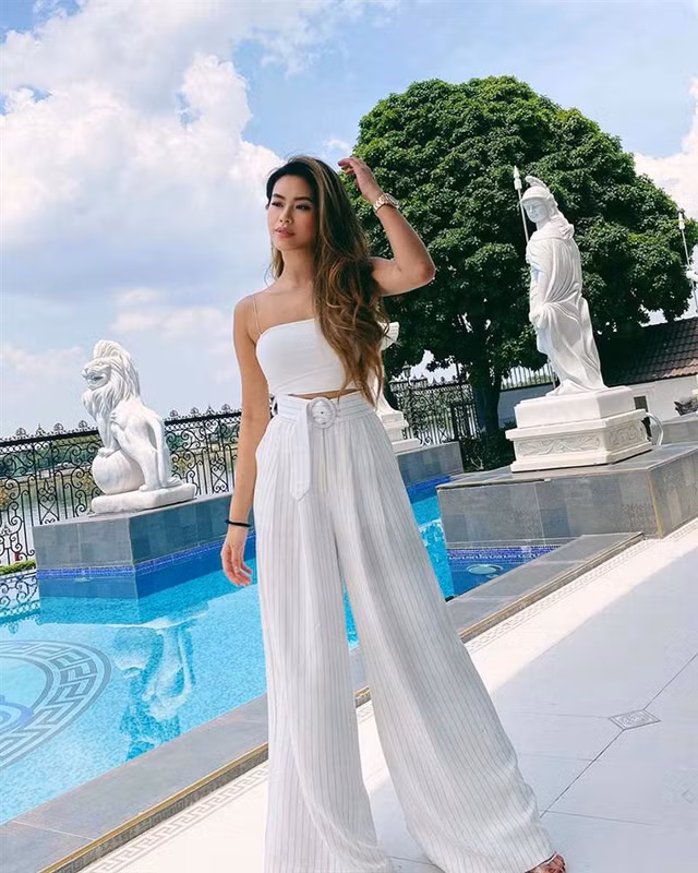 Để ăn nhập với màu xanh dương của bể, màu trắng của gạch tường cô nàng khi thì diện một chiếc short jeans và áo croptop trắng, khi thì một cây jumpsuit trắng hay một chiếc đầm baby doll màu xanh lá cho tiệp màu với cây cối.