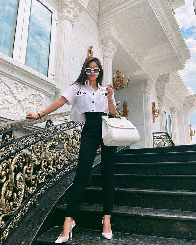 Trong hình Tiên Nguyễn là một người sành mặc khi diện một thiết kế áo croptop từ thương hiệu Chanel phối cùng giày cao gót cùng màu trắng, thêm chiếc túi hiệu size lớn yêu thích. Màu trắng cô mặc lại vô tình tiệp đồng màu cùng với sơn tường nhà cô. Nhằm tăng thêm chiều cao cũng như tạo hiệu ứng phần eo nhỏ lại, cô nàng còn khéo léo mặc một chiếc áo thun màu đen bên trong: không cần hở rốn vẫn vô cùng trendy.