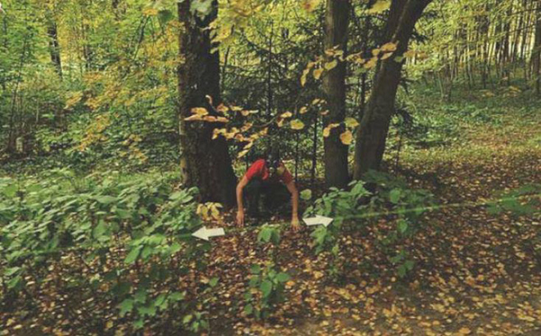 Một người đeo chiếc mặt nạ đậm chất đe dọa lẫn khó hiểu đang làm hành động kì cục bên vệ đường.