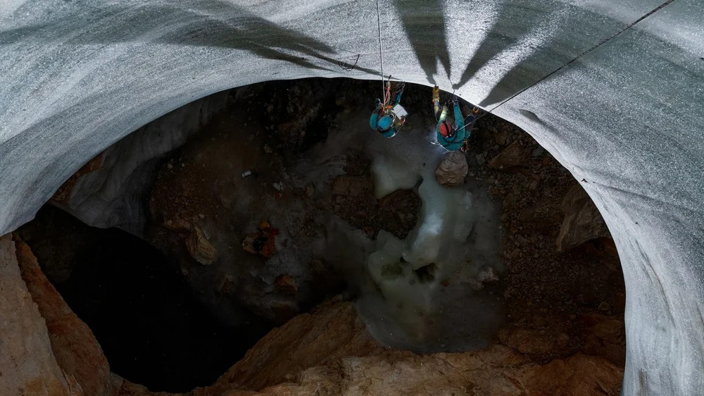 Sau bức tường băng cao 22 mét, nhà cổ sinh vật học Tanguy Racine (ở bên phải) và một đồng nghiệp dừng lại để lấy một mẫu của nó. Racine đã phát hiện ra rằng lớp băng gần đáy của hang động sâu 100 mét này có thể đã 5.300 năm tuổi. Băng đã tích tụ ở đây trong gần 2.000 năm qua. Ảnh: National Geographic