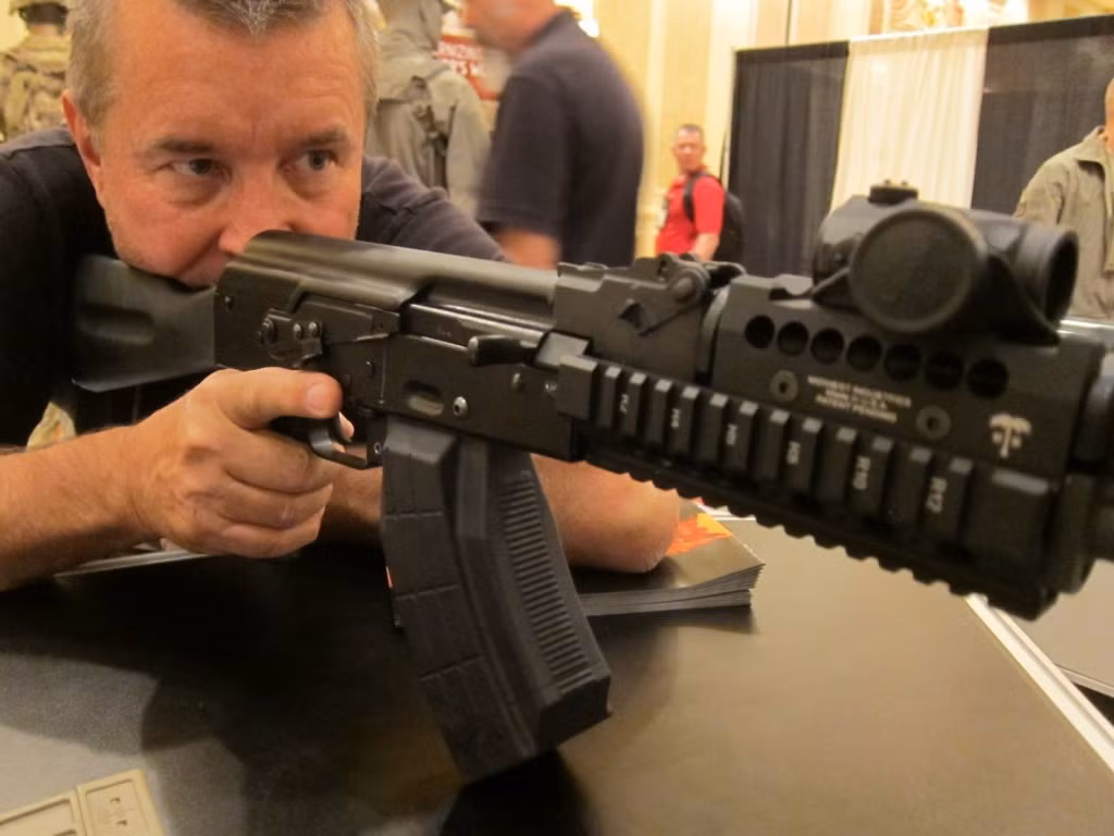 Nếu nắp hộp khoá nòng được làm cố định, súng trường Kalashnikov sẽ mất đi độ "dơ" mà súng vốn có khiến nó dễ bị kẹt đạn hơn khi cát, bụi chui vào trong. Vậy nên để gắn thêm ngắm vào súng AK, người ta thường tránh tác động vào nắp hộp khoá nòng và lắp kính ngắm ở... xa mắt xạ thủ như thế này. Nguồn ảnh: Pinterest.