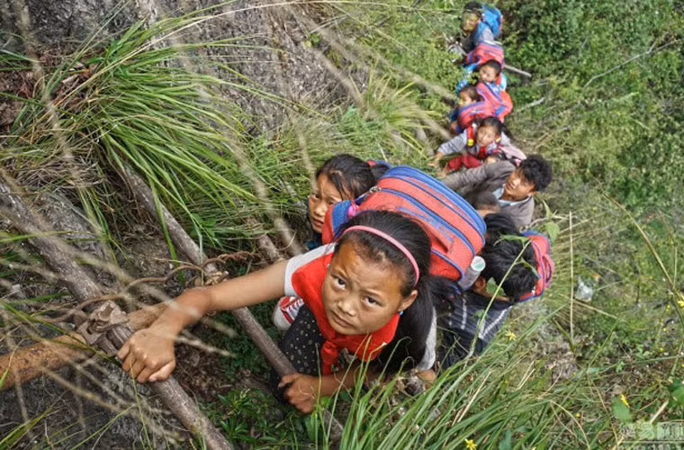 Các em học sinh Trung Quốc ở độ tuổi còn khá nhỏ đang cẩn thận leo lên một bậc thang để trở về nhà sau thời gian học ở trường. Chúng leo theo dây thang nguy hiểm này mà không có bất cứ đồ bảo hộ nào.