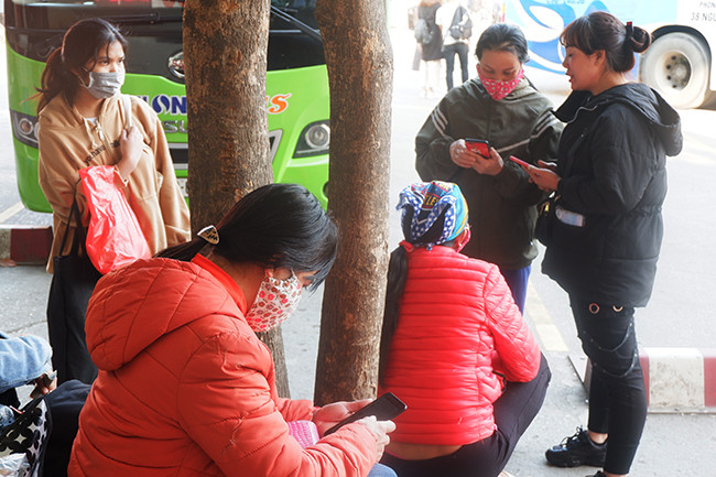 Nhiều người dân ngồi dùng điện thoại chờ xe chạy. Được biết, so với năm ngoái lượng khách đổ về Bến xe Mỹ Đình giảm 30% so với năm 2020.