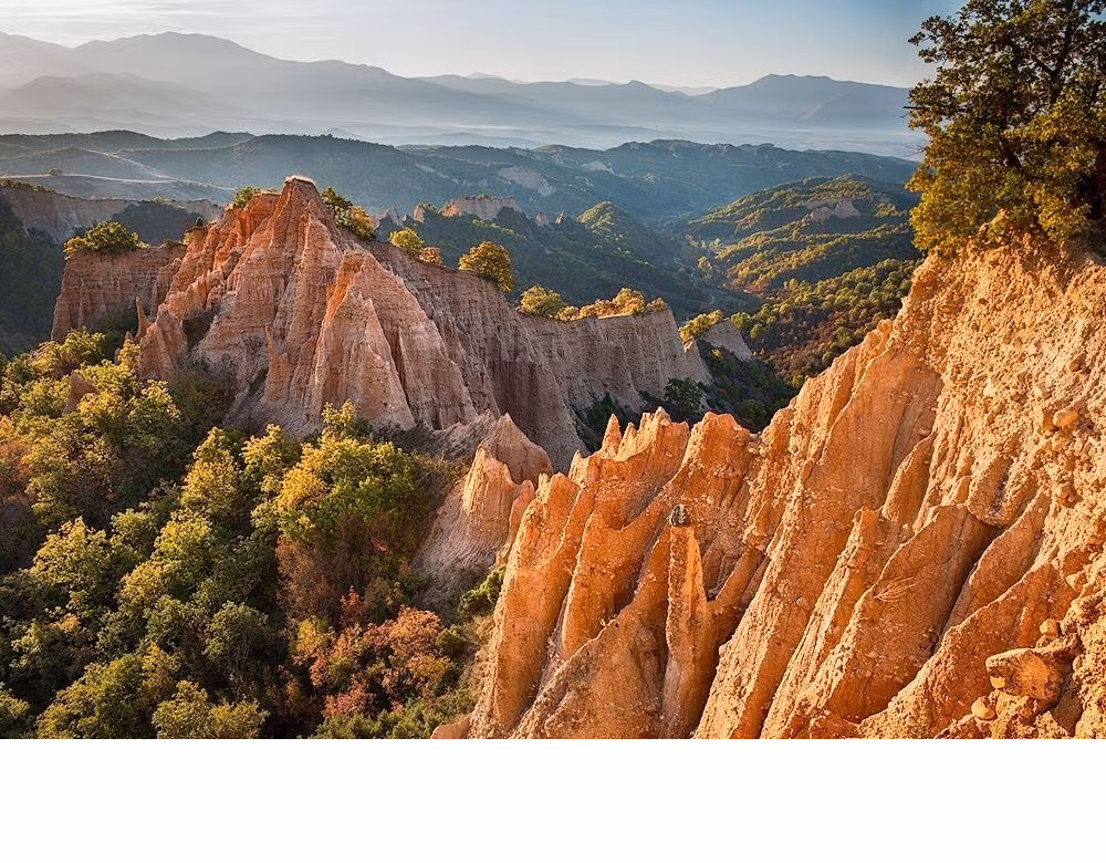  8. Kim tự tháp Melnik. Ở chân dãy núi Pirin là vùng Kim tự tháp Melnik hùng vĩ trải dài, được chia thành ba nhóm: Melnik, Karlanovo và Rozhen. Những hình dạng độc đáo được hình thành từ cát tự nhiên và điêu khắc bằng sự xói mòn đất, có niên đại lên tới bốn, năm triệu năm. Với độ cao trên 100m, những ngọn tháp đá sừng sững đã được phong hoá tự nhiên thành chóp nón gợn sóng, các cột đá hình mũi tên và đỉnh núi với cỏ dại và cây rụng lá bao phủ ngọn và những nếp gấp quanh chúng. Du khách có thể thăm quan khi đi theo những cung đường mòn đi bộ từ Melnik và Tu viện Rozhan ở gần đó, và mặc dù bạn có thể leo lên đỉnh những ngọn kim tự tháp, hãy cẩn thận vì chúng rất dốc và cát khá lún.