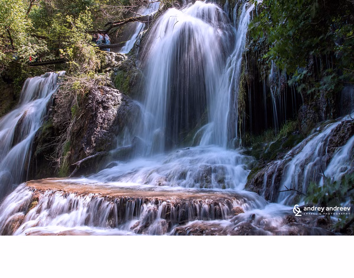  7. Thác Krushuna. Thác Krushuna là một trong những hệ thống thác nước lớn nhất của xứ sở hoa hồng với độ cao lên tới 20m. Một con đường sinh thái sẽ đưa du khách lên các bậc thang, dọc theo vài cây cầu, đi qua những bể nước tự nhiên nhỏ giữa những tảng đá phủ đầy rêu phong. Bạn còn có thể bơi trong một bể nước khoáng thiên nhiên với nhiệt độ 58oC. Màu xanh lục lam ngăn ngắt của dòng nước là từ những đá vôi được cho là có khả năng chữa bệnh. Ẩn mình giữa những tảng đá xung quanh là một hệ thống hang động cổ, nơi các nhà sư chạm khắc nên nơi ở của họ từ thế kỷ 13 và 14, thậm chí du khách còn có thể thăm qua một nhà thờ nhỏ được khắc từ một trong những tảng đá ở đây.