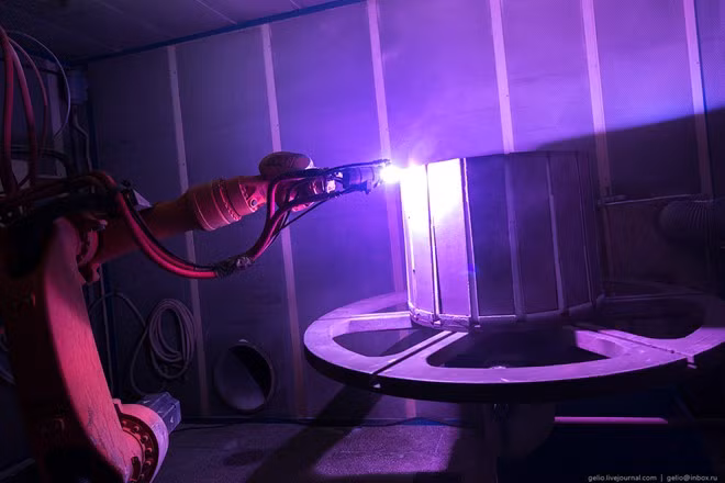 Cánh tay robot TSZP-MF-P-1000 đang xử lý phần ống xả của động cơ bằng công nghệ nhiệt sơn plasma.