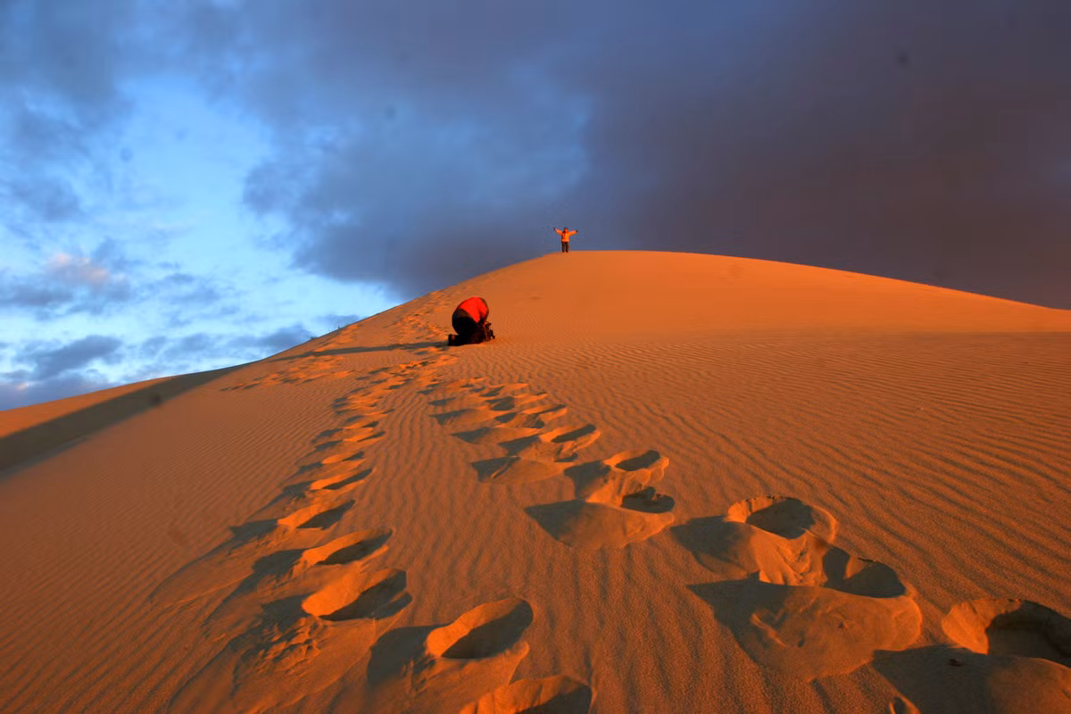 Nhưng ngày nay, đàn lạc đà đi trên những dải cát màu đỏ bất tận của Minh Sa Sơn không còn chở những thứ hương liệu, gia vị và vải vóc đắt tiền như xưa nữa, mà chở du khách với mức giá 100 Nhân dân tệ mỗi lượt. Ảnh: T-westchina.com.