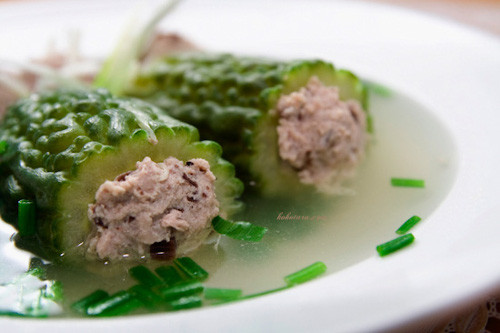 Thịt nạc băm nhuyễn, mộc nhĩ, nấm hương ngâm nở, rửa sạch, thái nhỏ. Hành khô, tỏi bằm nhuyễn. Ướp thịt với bột ngọt, muối, tiêu, nấm hương, mộc nhĩ, hành lá, hành khô, tỏi bằm, rau mùi. Sau đó nhồi thịt đã ướp vào mướp đắng. Đun nồi nước sôi thì thả mướp đắng vào, giảm lửa, hớt bọt, rồi nêm gia vị vừa ăn. Mướp đắng chín mềm, tắt bếp, múc ra bát. Ảnh: kokotaru