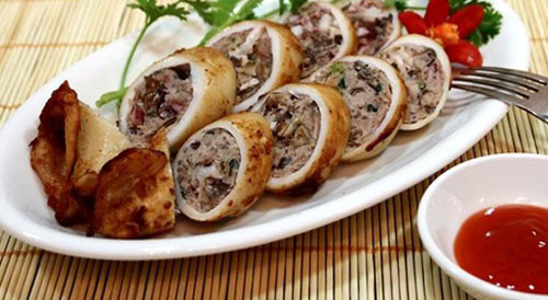 Nêm gia vị, hạt nêm, hạt tiêu, xì dầu, ướp ngấm rồi nhồi vào mực ống. Ghim đầu mực để thịt không bị rời ra. Bọc giấy bảo quản rồi cho vào lò vi sóng quay. Mực chín để nguội và cắt thành khoanh bày ra đĩa. Ảnh: ktdt