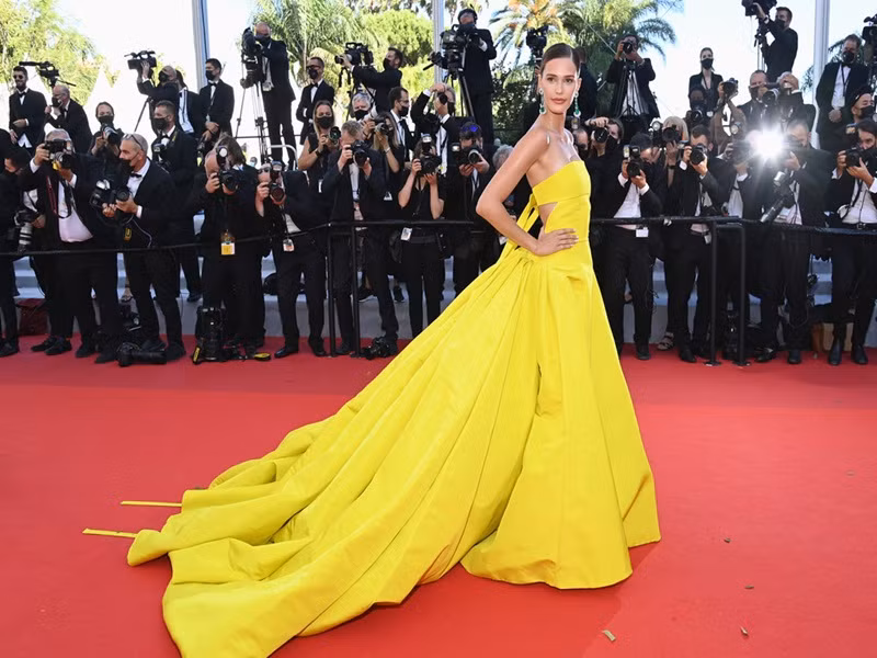 Người mẫu Noel Capri Berry cũng mặc gợi cảm trên thảm đỏ Cannes 2021 ngày thứ 8. Cô chọn đầm hở lưng màu vàng.