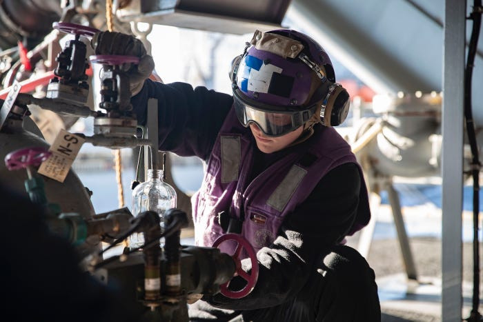 Trên tàu sân bay, các nhân viên mặc áo bảo hộ màu tím sẽ phụ trách việc kiểm soát nhiên liệu cho máy bay trên tàu. Nguồn ảnh: BI.