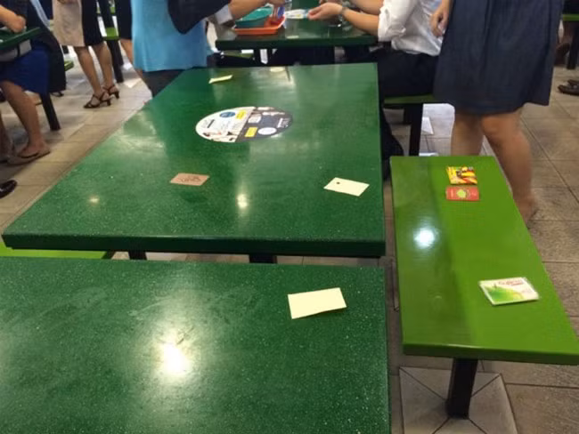 Tại các trung tâm ăn uống ngoài trời đông đúc thật khó để vừa mua được đồ ăn vừa có chỗ ngồi ưng ý. Vì vậy, người Singapore thường kiếm cho mình một chỗ ngồi bằng cách đặt một tờ giấy vào chỗ mình đã chọn (kiểu giữ chỗ) rồi mới đi xếp hàng mua đồ ăn.