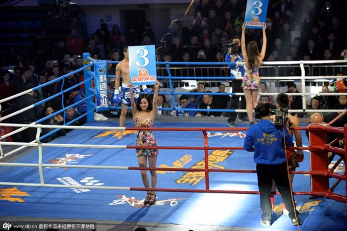 Hai cô gái cầm biển khi trận đấu tạm ngừng. Sự hiện diện của họ khiến trận đấu trở nên hấp dẫn hơn.