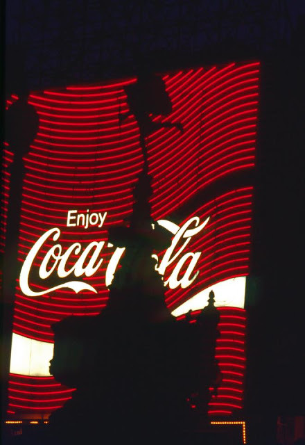 Tượng đài thần Eros in bóng lên bảng quảng cáo nước giải khát Coca Cola ở giao lộPiccadilly Circus.Ảnh: Vintag.