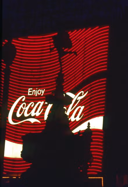 Tượng đài thần Eros in bóng lên bảng quảng cáo nước giải khát Coca Cola ở giao lộPiccadilly Circus.Ảnh: Vintag.